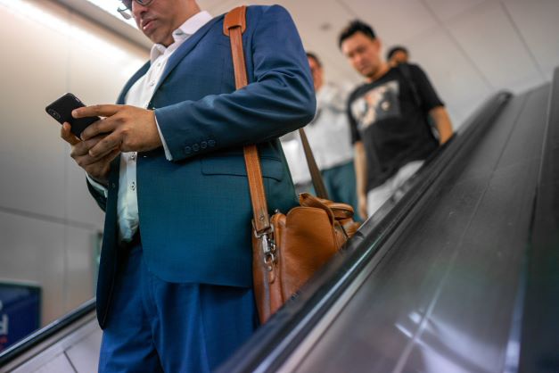 Un homme avec son telephone est sur un escalator 