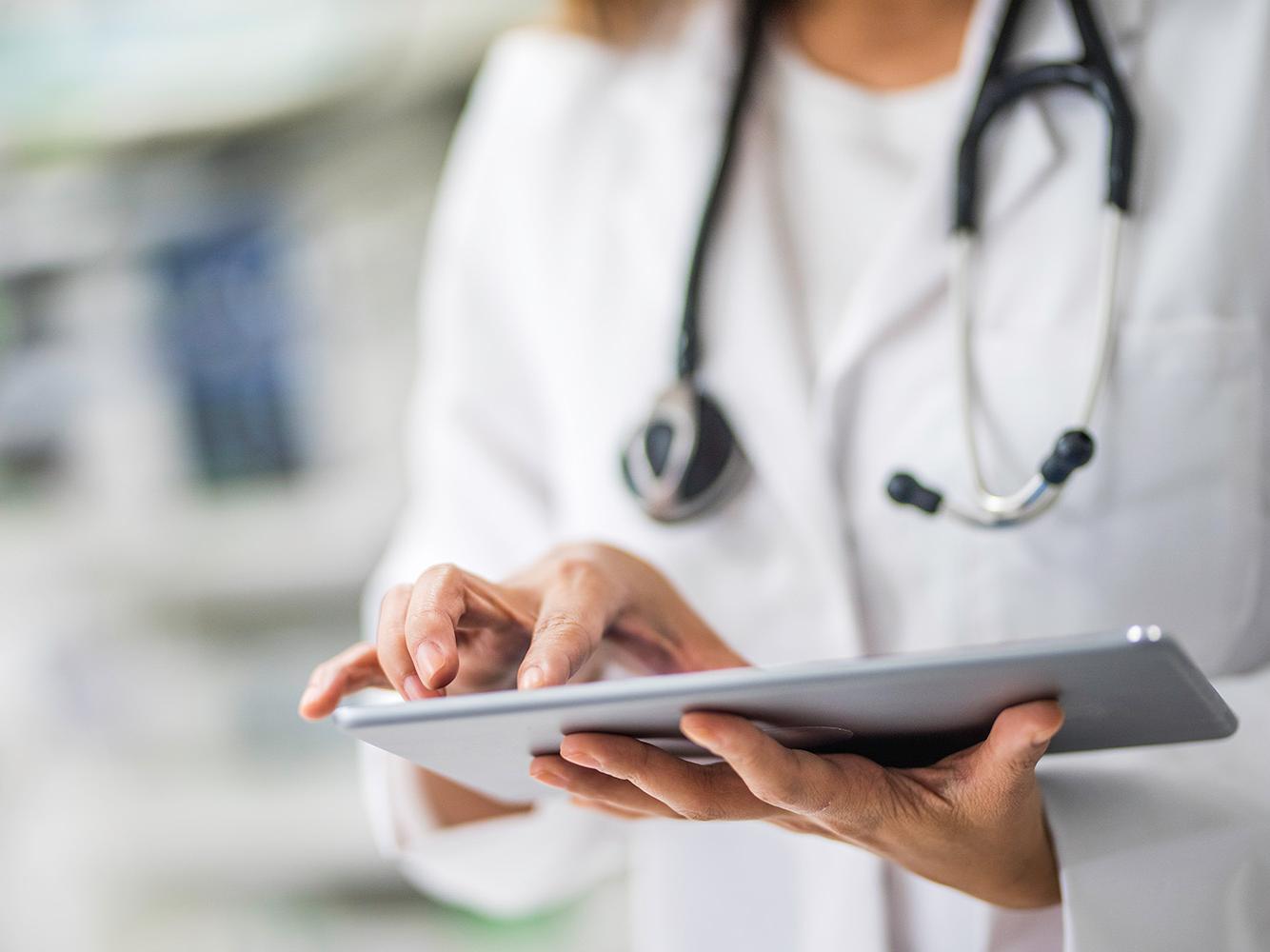 mains d'un médecin consultant une tablette connectée