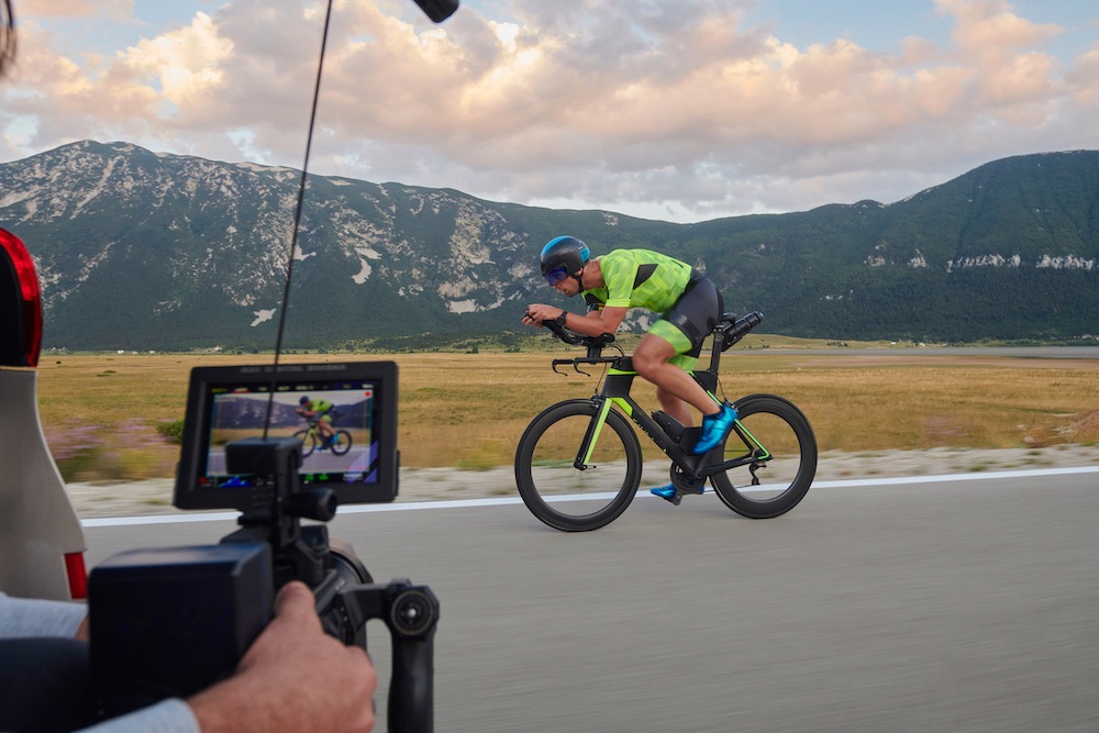 Caméra portative filme un cycliste en pleine vitesse sur une route, payasgae de montagnes
