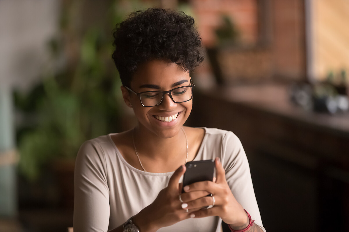 Femme souriant devant son écran de téléphone