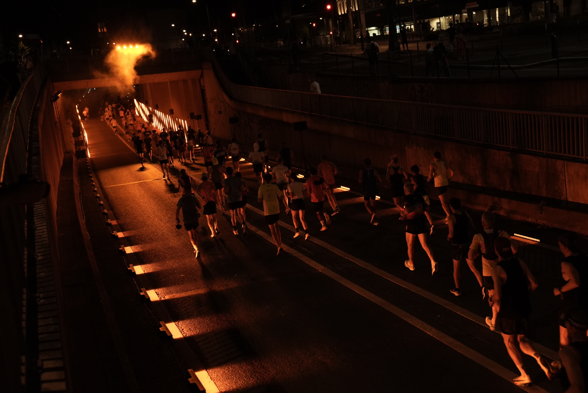 Marathoniens entrant dans un tunnel de nuit illuminé aux couleurs Orange
