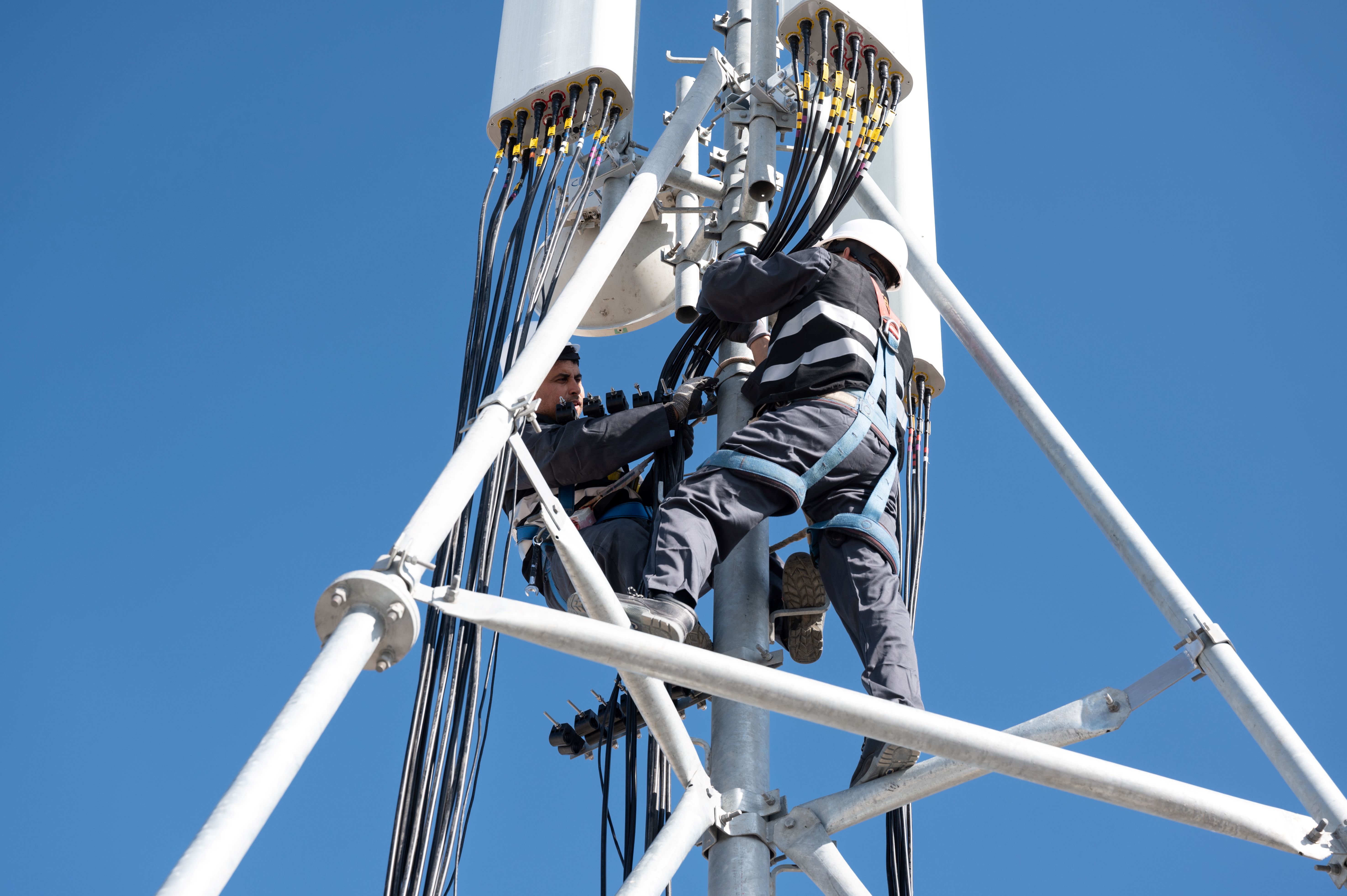 deux hommes en hauteur sur une antenne pilône 