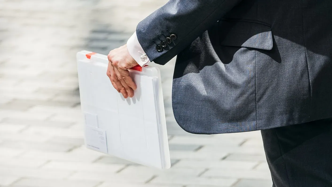 Un homme marche avec un porte document dans la rue