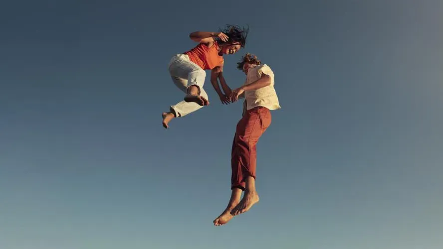 un couple souriant se tient la main dans les airs