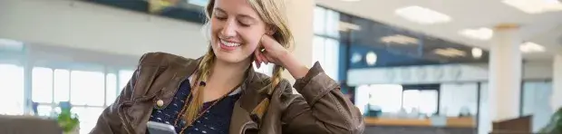 Une femme consulte un mobile sur un banc dans un aéroport