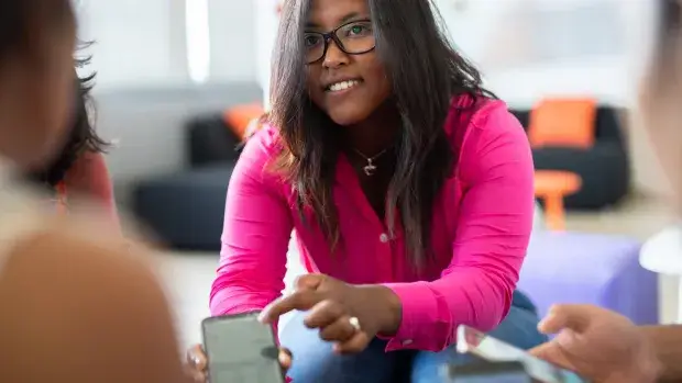 Une jeune femme africaine montre un mobile en réunion