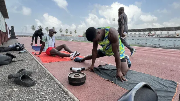 Photo d'Arthur Cissé qui s'échauffesur un terrain de course avec d'autres athlètes