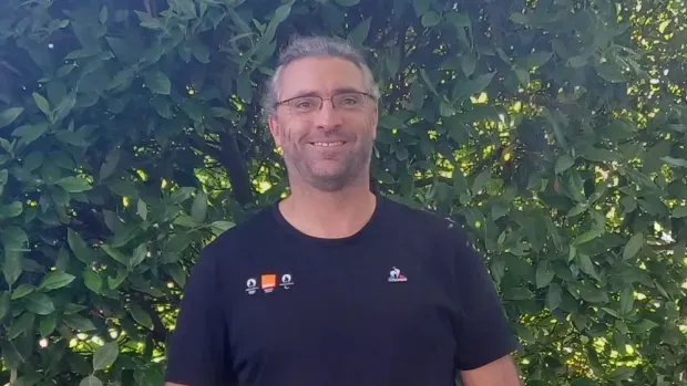 Cédric, Network Expert, smiling in front of a bush 