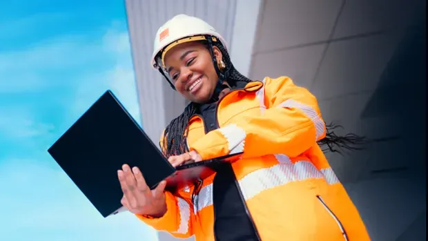 An Orange technician smiling and working on her laptop