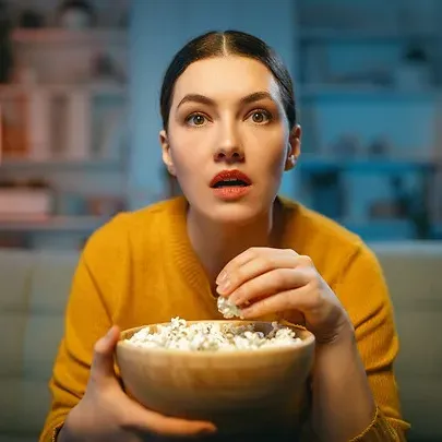 Photo d'une femme mangeant du pop corn et regardant la télé 