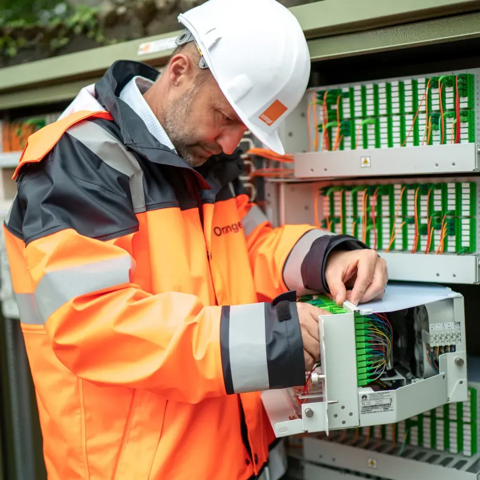Technicien Orange devant une tablette de contrôle avec des câbles de fibre optique