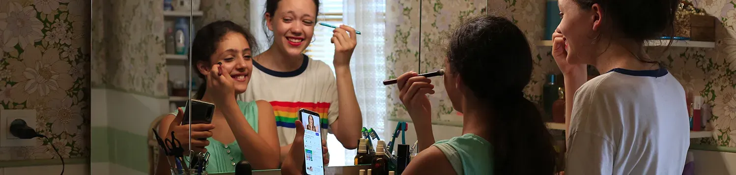 Deux adolescente se maquillent et se prennent en selfie dans la salle de bain