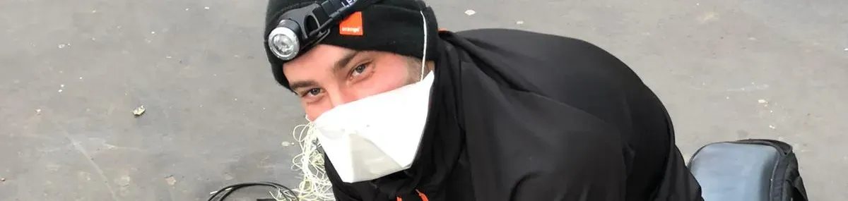 Un technicien Orange au travail avec un masque