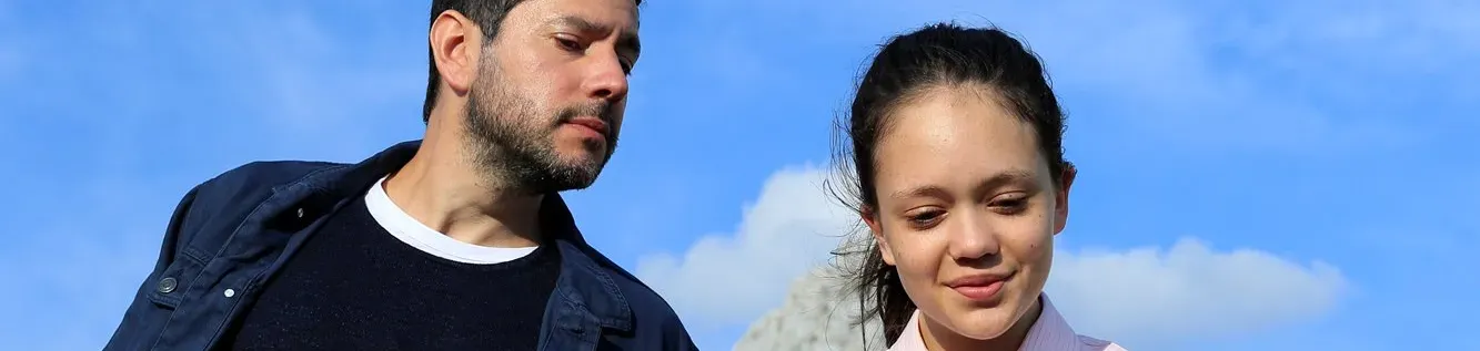 Un père regarde le mobile de sa fille par dessus son épaule