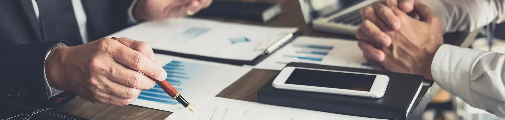 Deux hommes discutent à une table sur laquelle figure des graphiques