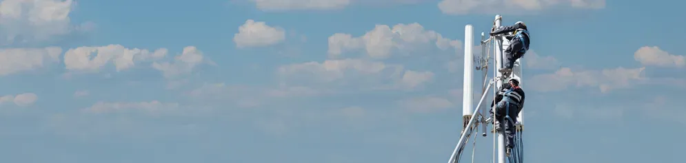 2 techniciens posent un antenne en hauteur sur un toit