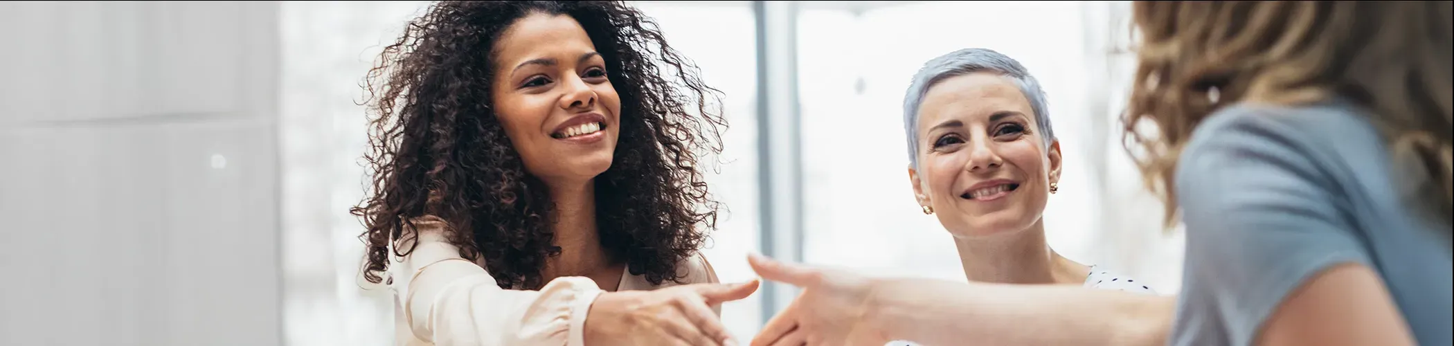 trois femmes en réunion se saluent avec poignée de mains