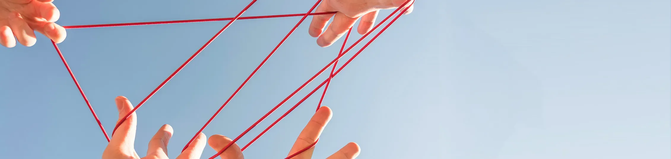 Des mains entrelacées d'un fil de laine orange