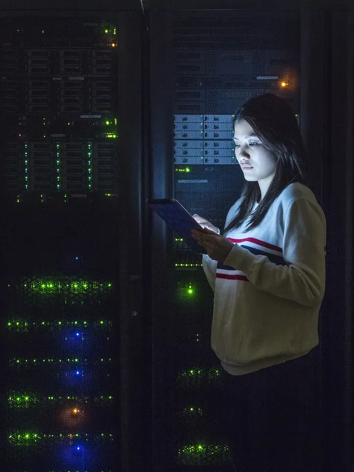 Une femme avec une tablette devant des servers 