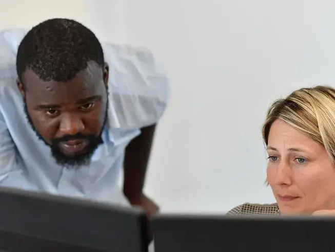 deux personnes observent un écran d'ordianteur