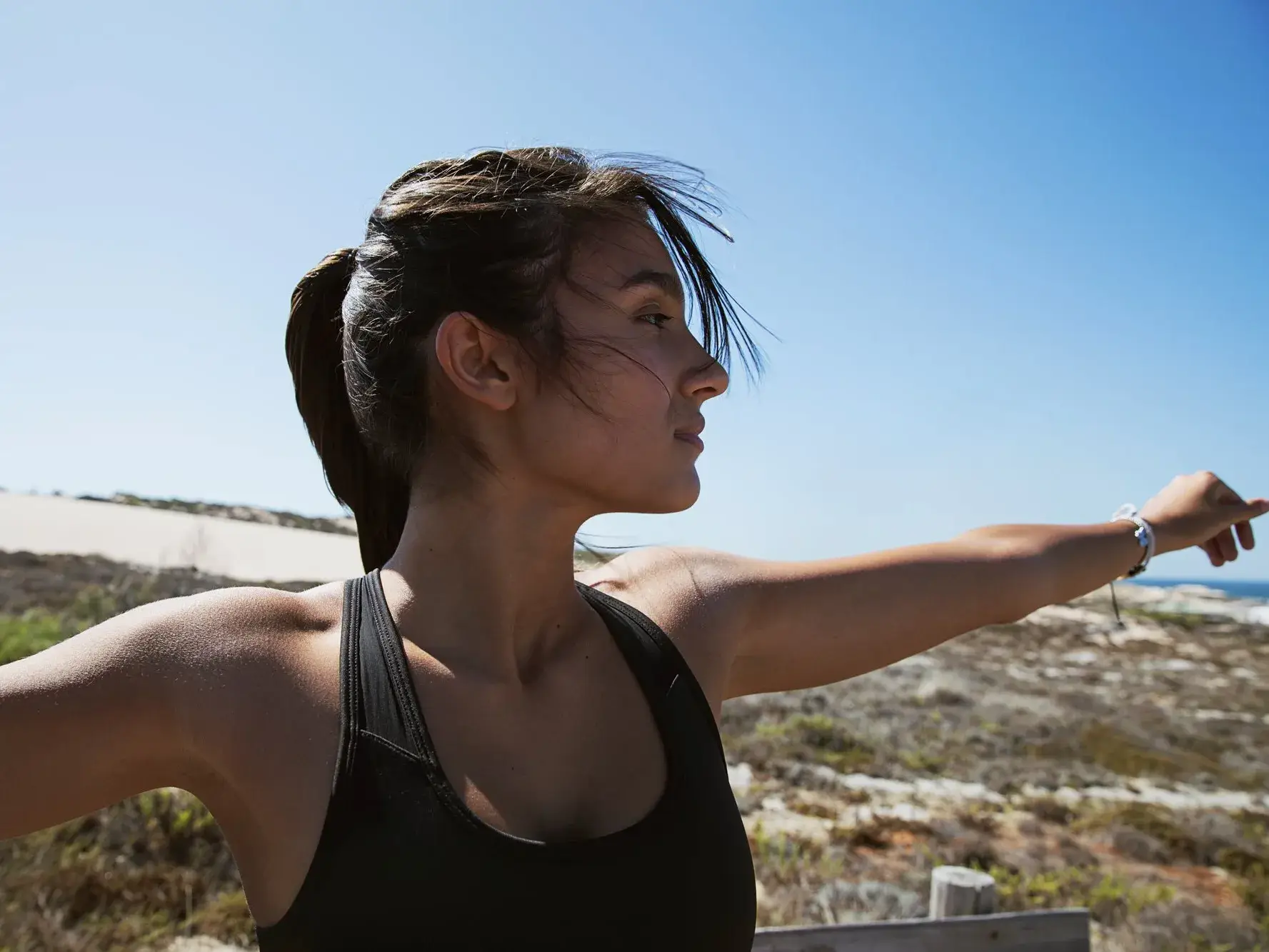 Femme écarte les bras sur une plage
