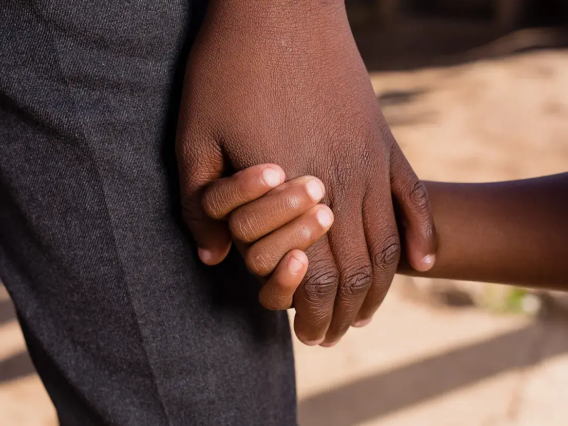 Une main d'adulte tient une main d'enfant 