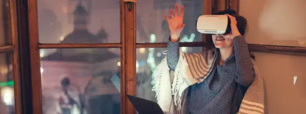 jeune femme la nuit sur son canapé, souriante avec casque réalité virtuelle