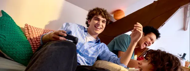 Photo d'un homme jouant à la console avec 2 amis